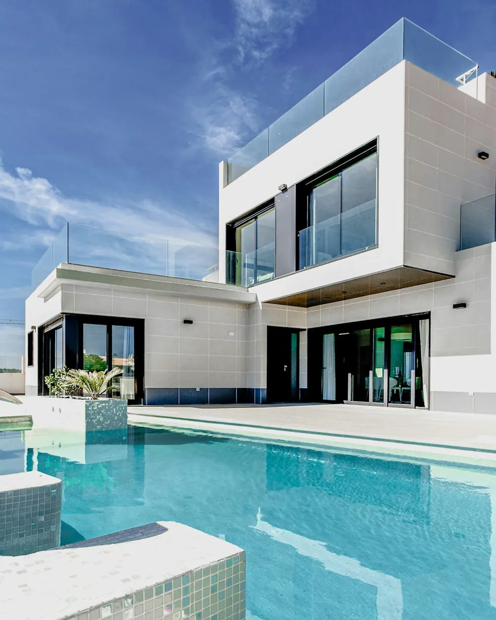 A white contemporary villa with a reflecting pool and palm trees