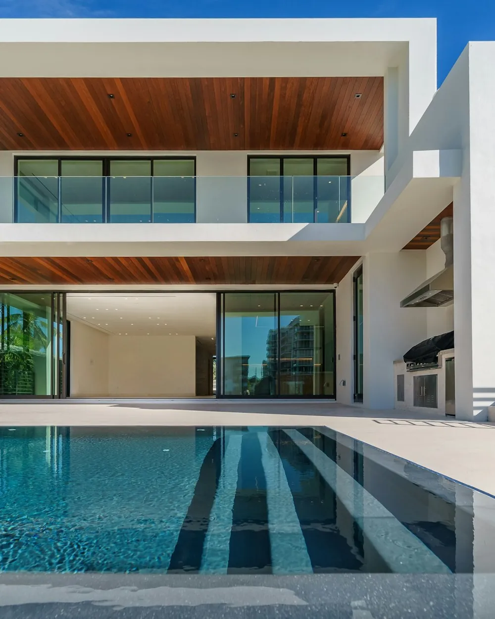A modern villa with a pool and timber-lined terrace in the late afternoon sun