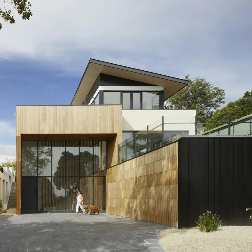 A low-slung modern home with a timber screen and gravel courtyard