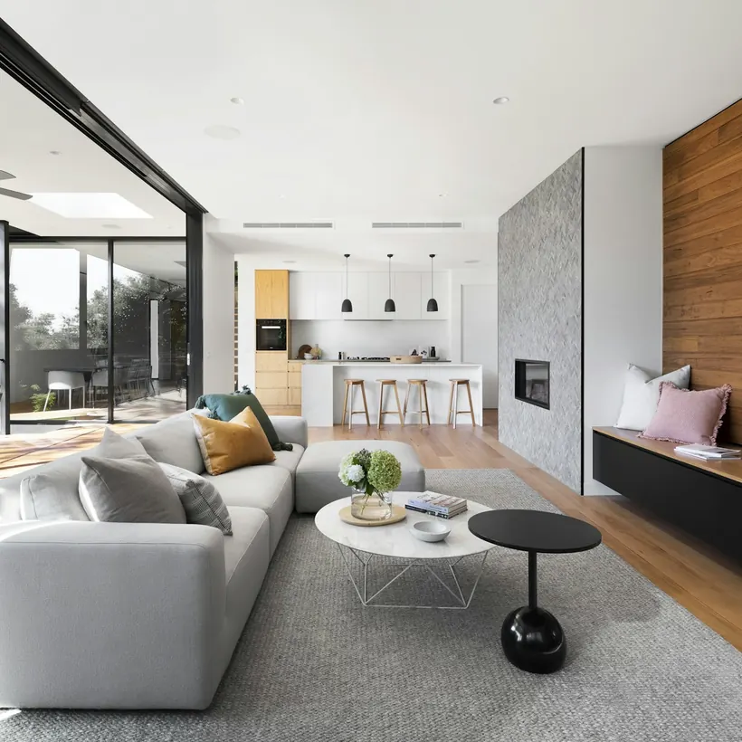 A bright living room with a dark feature wall, timber floors and sliding glass doors